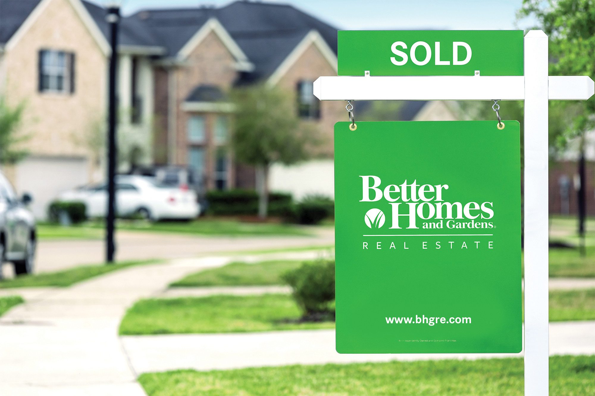 Image20250414095109 A green sign that says sold in front of some houses.